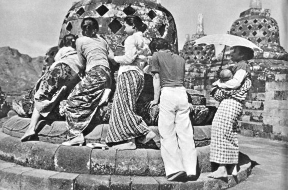 Para pengunjung berusaha memegang arca yang ada dalam stupa di Boroboedoer. Njis, E. Breton de, “Tempo Doeloe - Fotografische documenten uit het oudeIndie 1870-1914", Amsterdam E.M. Querido’s Eitgerbers M.J. 1961.